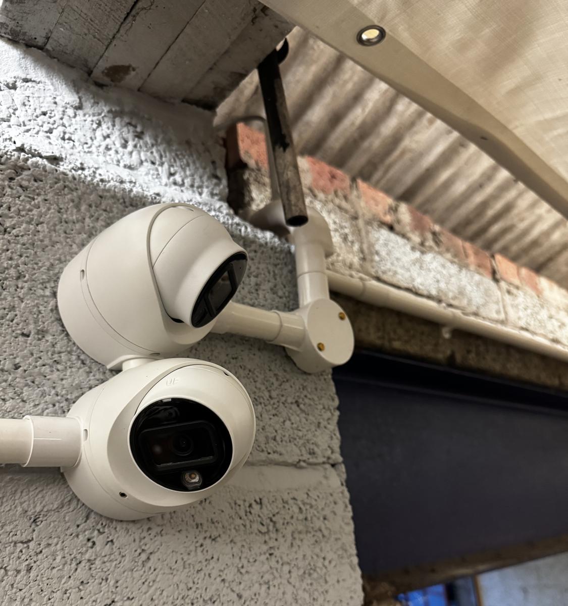 Two cameras on brackets covering a yard