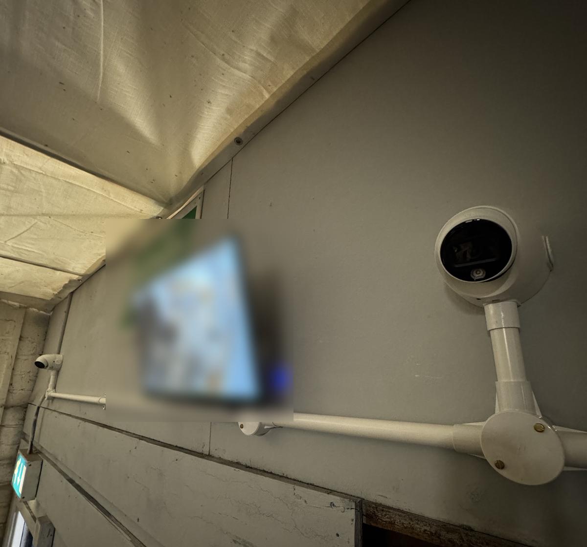 Camera and staff monitor inside a business (screen blurred)