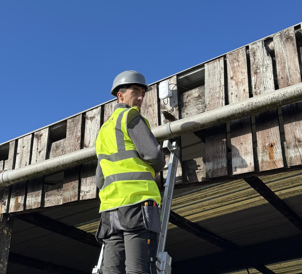 Techtrix engineer fitting a wireless link high on a barn wall