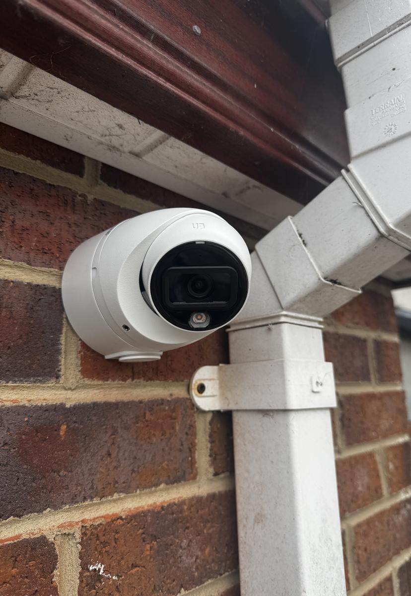 White CCTV camera beside a downpipe on a brick house in Hillsborough
