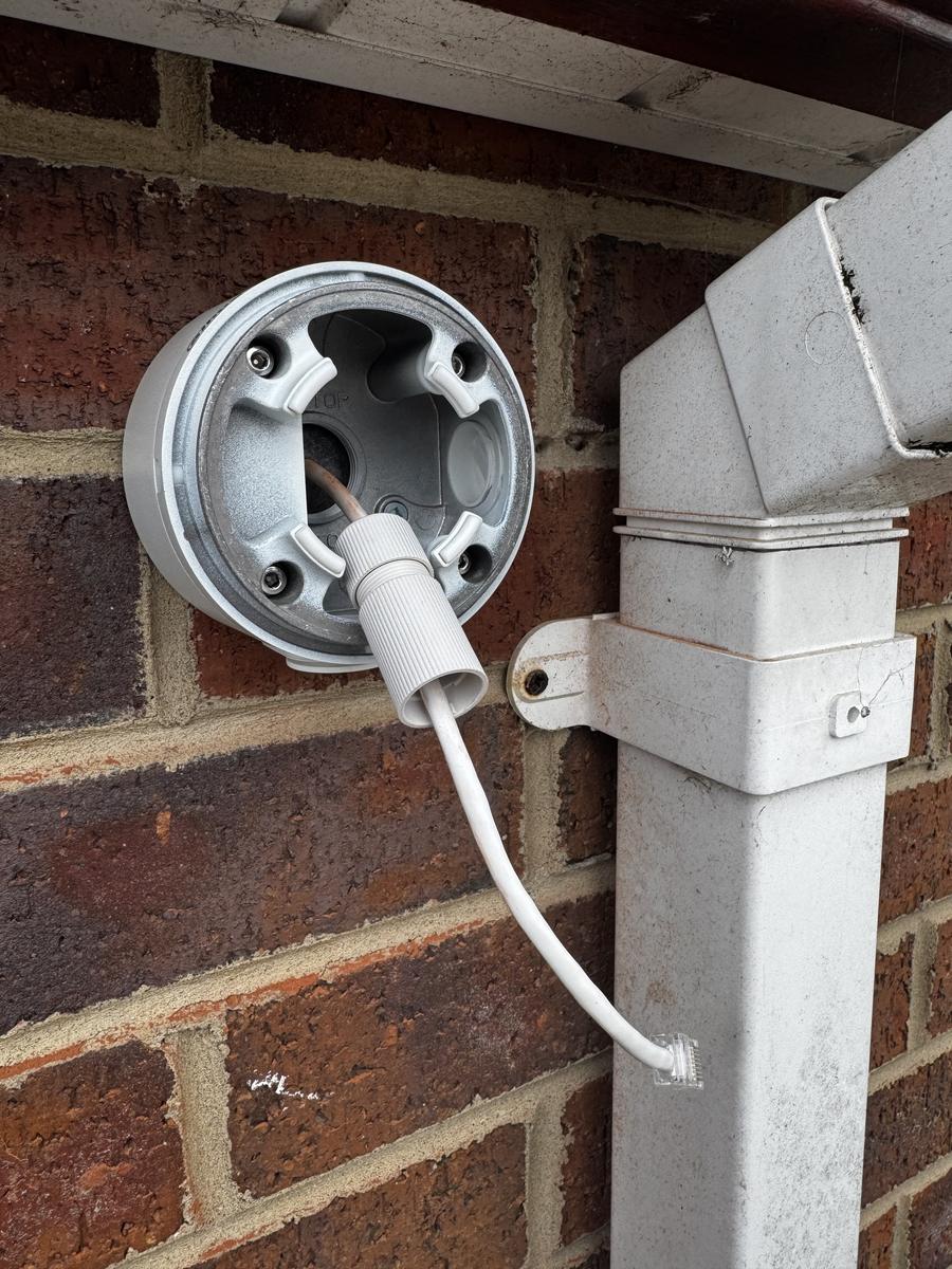 CCTV junction box being fitted, with the cable taken in behind the downpipe