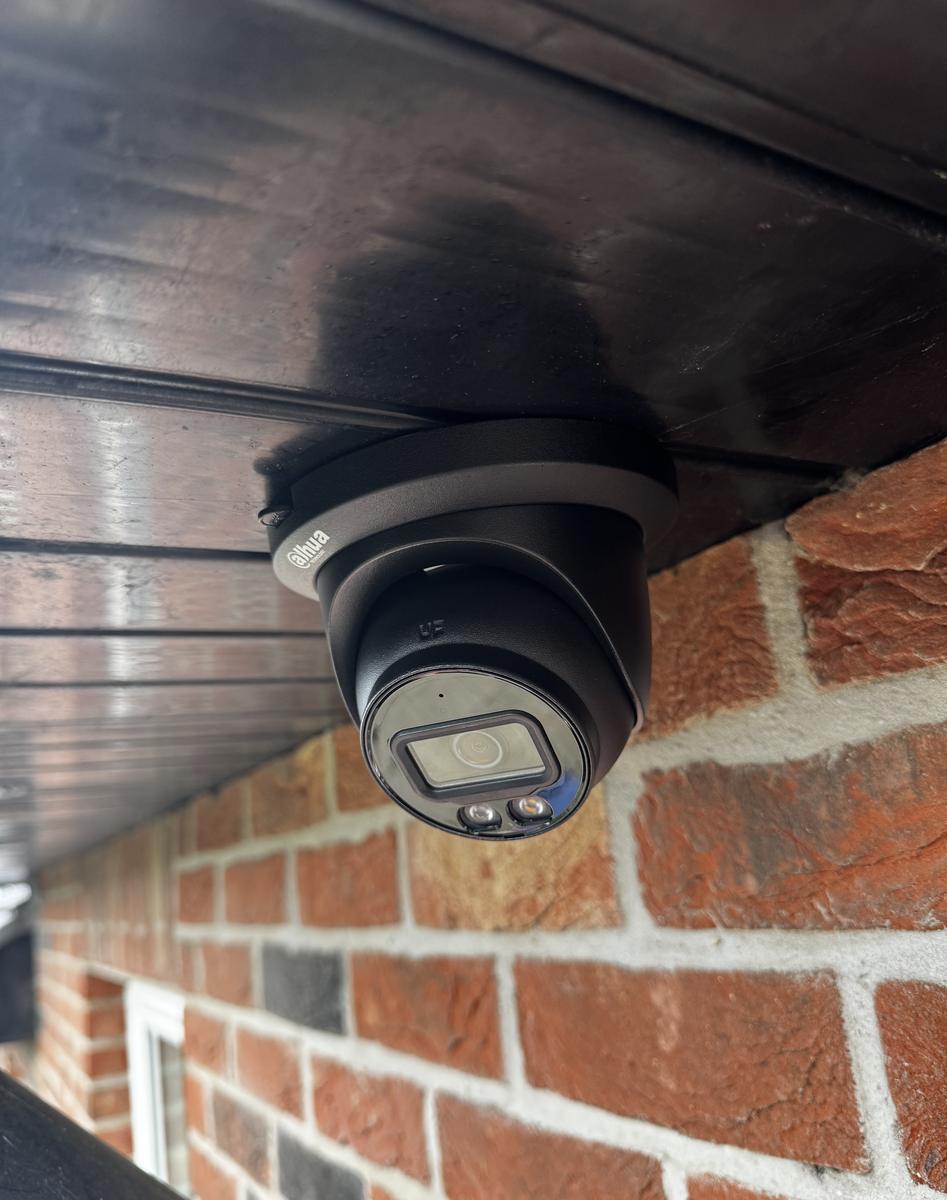 Black dome camera under the soffit of a brick house in Kinallen
