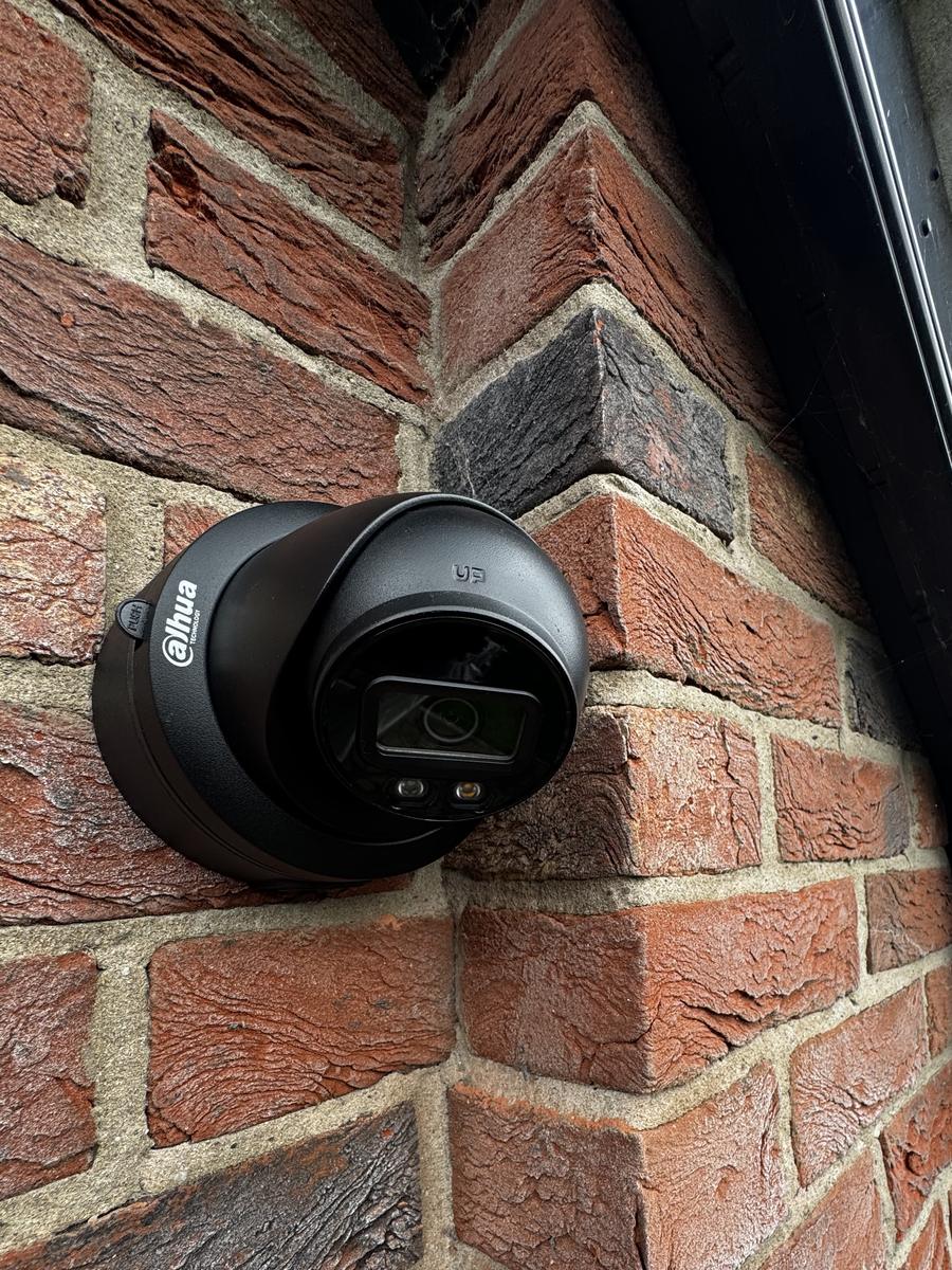 Black dome camera on the corner of a brick house